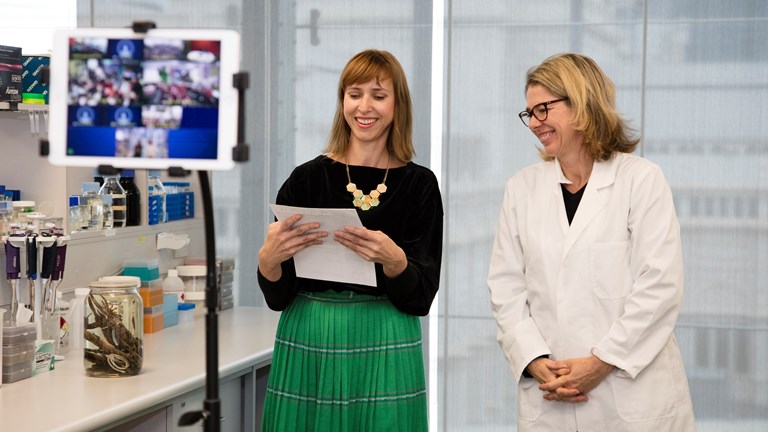 Two museum staff presenting to an iPad which shows schools watching from the classroom.