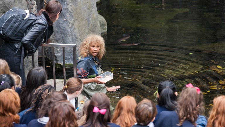 Woman talking to a crowd about the eels in the pond