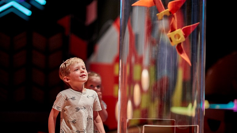 Young boy playing with suction tube exhibit in the Ground Up exhibition at Scienceworks