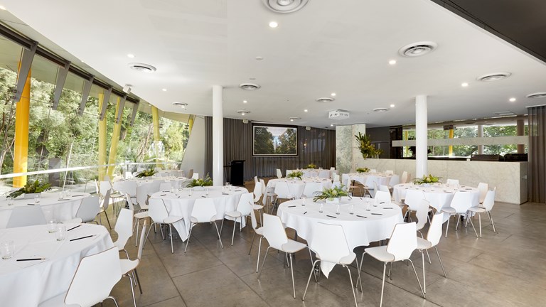 Room set up with round tables and chairs with white tablecloths