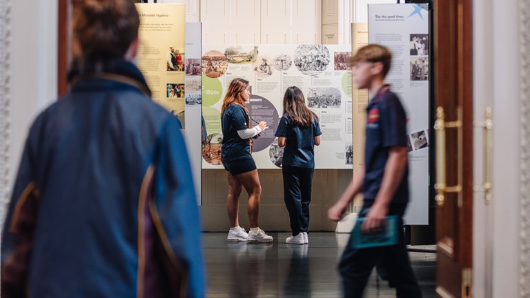 Four students with workbooks looking in a gallery.  