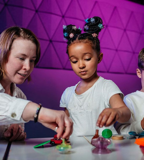 A teacher and two children playing with play dough