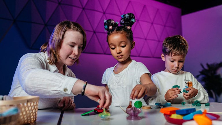 A teacher and two children playing with play dough