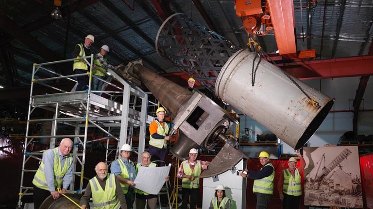 Group of people in high-vis vests standing by a large telescope