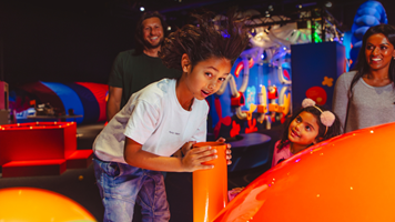 A girl places her head and air above a bright orange air vent.