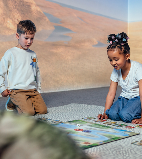 A teacher and two young children playing a board game.