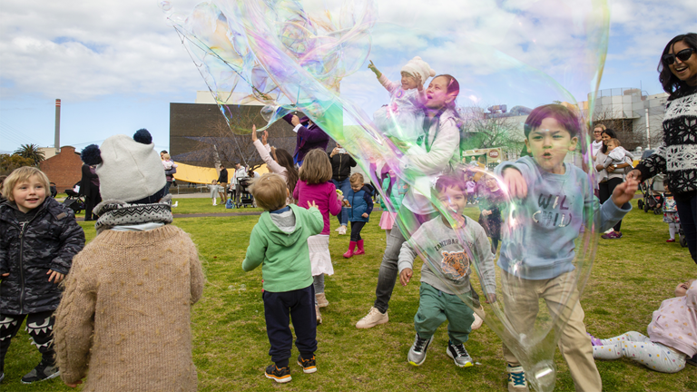 Children chasing giant bubbles on the Arena of Scienceworks in Melbourne.