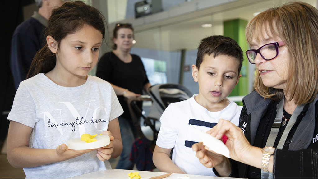 Volunteer assists visitors during school holiday activity at Melbourne Museum.